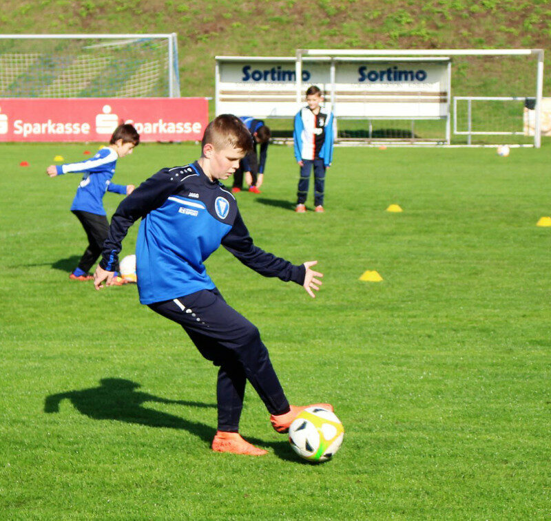 Ein etwa 12-jähriger Junge kickt konzentriert einen Ball