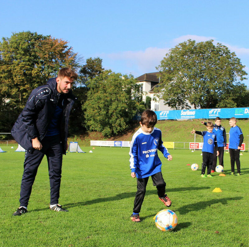 Trainer instruiert Jungen, der kurz vor einem Fußball-Schuss steht.